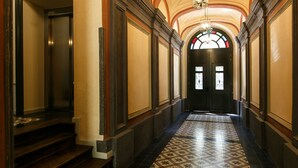A hallway with a patterned floor, a staircase, and a door with a stained glass window. - Otium Old Town Sarego (Kraków)
