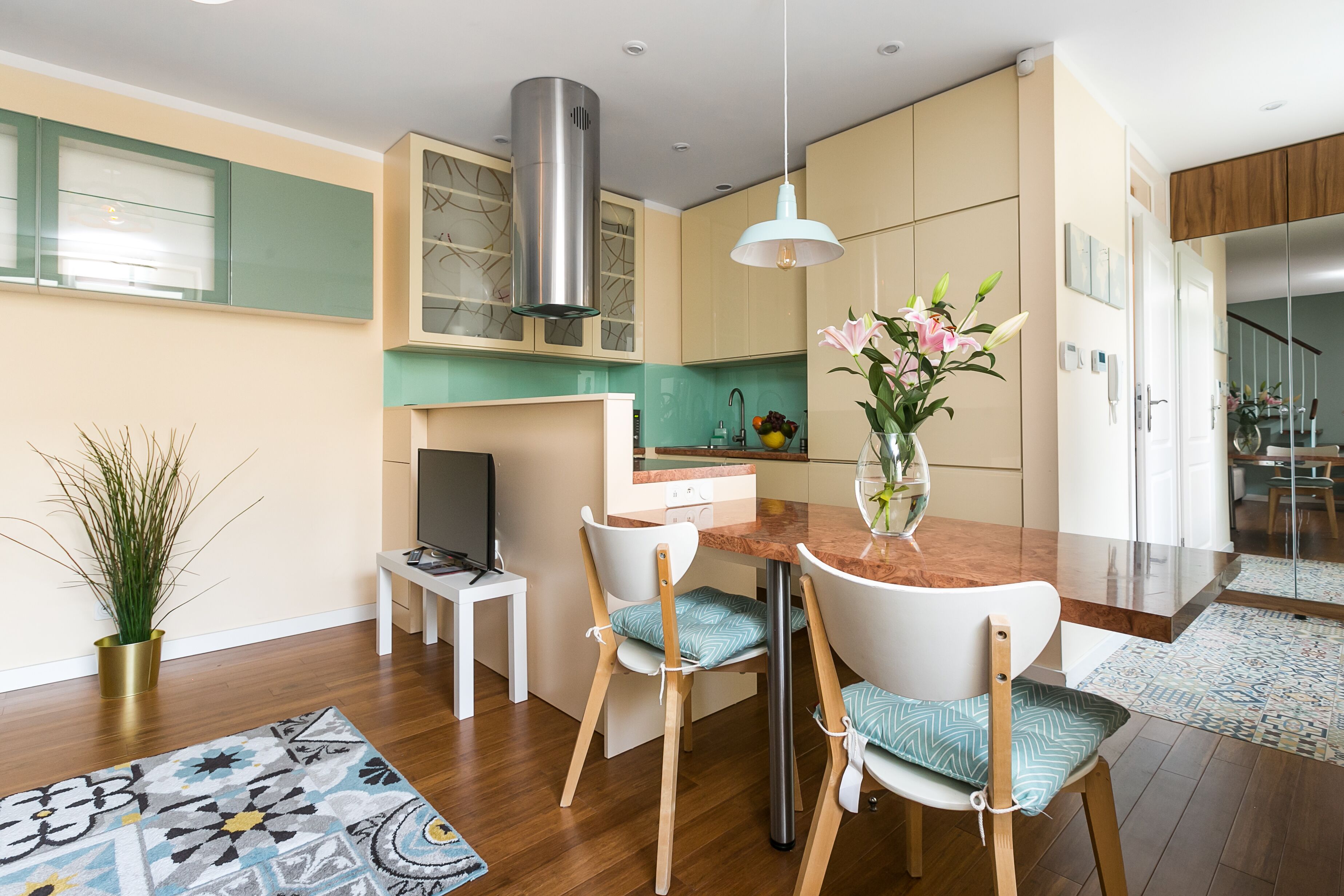 A modern kitchen with a central island, white chairs, and a hanging pendant light.