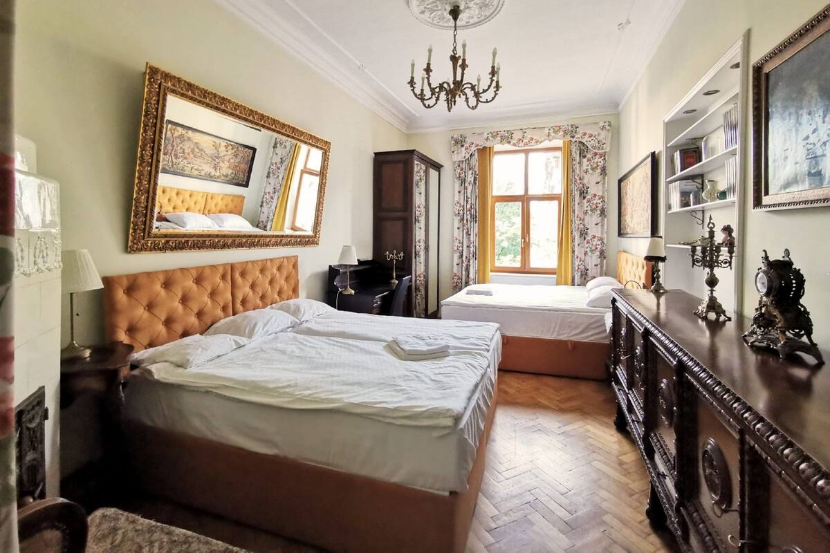 Ein Schlafzimmer mit zwei Betten, einer Chandelier, einem großen Spiegel und einer hölzernen Kommode.