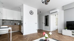 A modern kitchen with white cabinets, a herringbone wood floor, and a dining area with a white table and chairs. - Otium Old Town Sarego (Kraków)