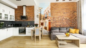A modern kitchen with white cabinets and a brick wall mural. - Otium Old Town Sarego (Kraków)