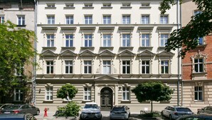 A multi-story building with a symmetrical facade, large windows, and a central entrance. - Otium Old Town Sarego (Kraków)