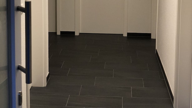 A hallway with a white door, a blue door frame, and a dark tiled floor. - Ferienpark Thüle (Friesoythe)