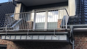A residential building with a brick facade, a balcony with metal railings, and a tiled roof. - Ferienpark Thüle (Friesoythe)