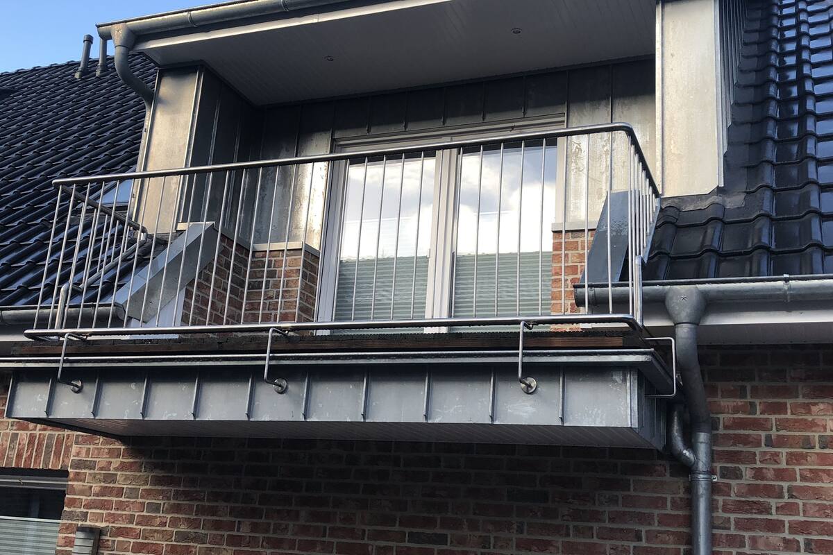 Un immeuble résidentiel avec une façade en briques, une balustrade en métal et une fenêtre avec des stores.