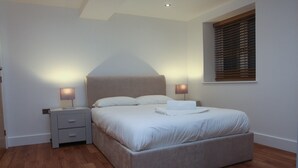 A bedroom with a bed, nightstands, and a window with blinds.