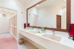 A bathroom with two sinks, a large mirror, and a red candle holder.