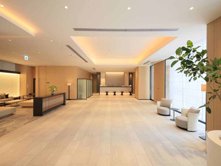 Un vestíbulo amplio con mostrador de recepción, zona de estar y ventanas grandes.