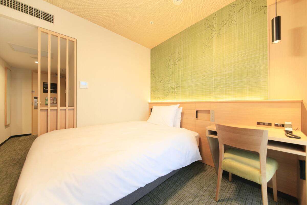 Ein Hotelzimmer mit einem großen Bett, einem Schreibtisch und einem Stuhl.