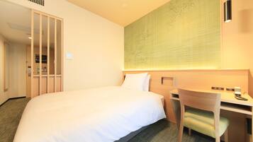 A hotel room with a large bed, a desk, and a chair.