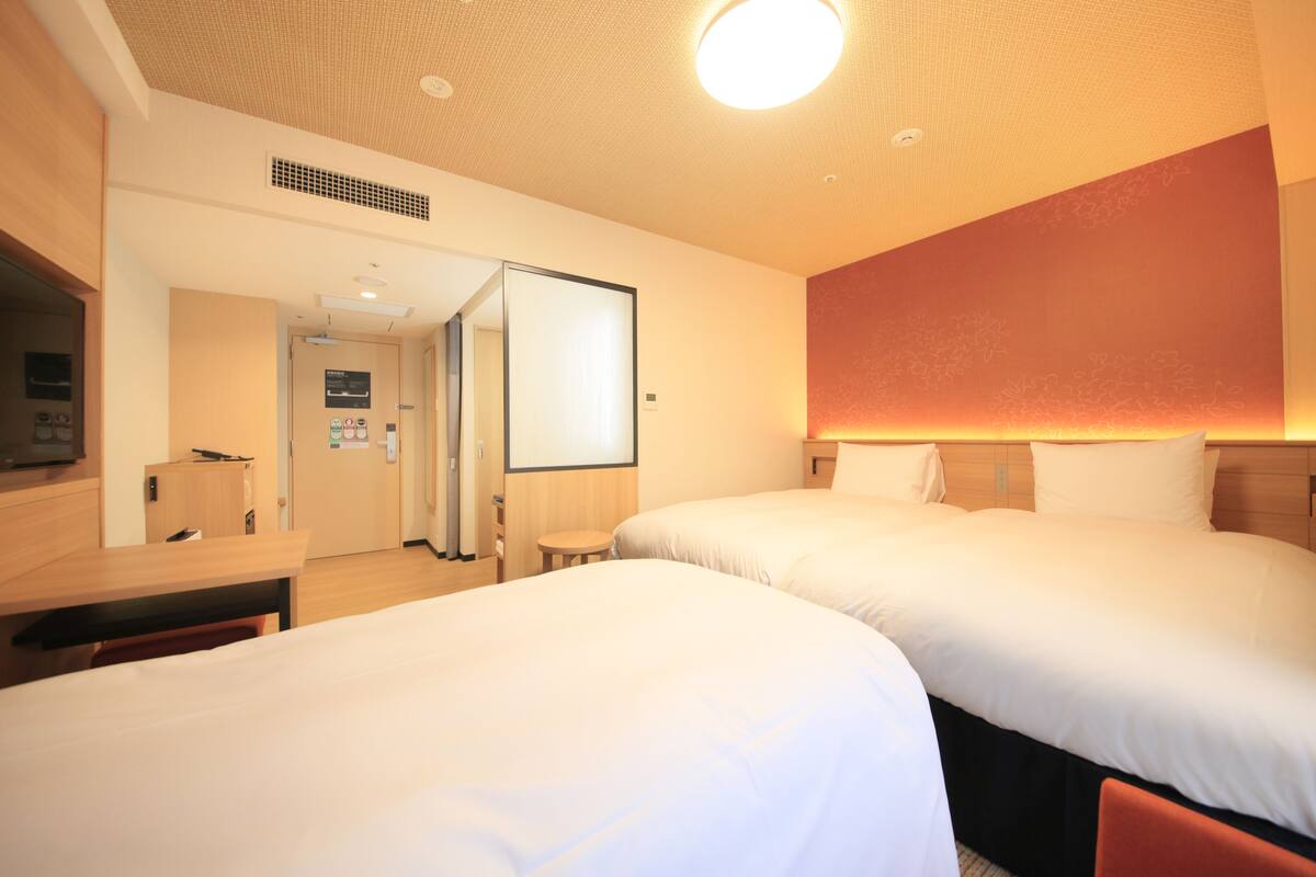 Ein Hotelzimmer mit zwei Betten, einem Schreibtisch und einem Spiegel.