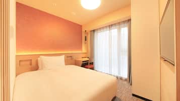 Una habitación de hotel con una cama grande, un escritorio, una silla, un armario y una ventana con cortinas.