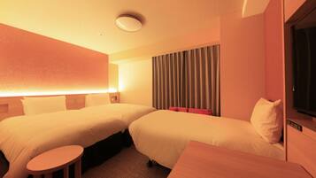 A hotel room with two beds, a small table, a TV, and a curtain.