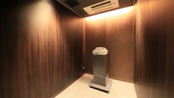Un ascenseur moderne avec une finition métallique, un panneau de commande et une unité de ventilation au plafond.