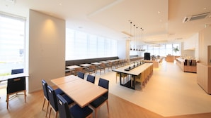 Un espace de restauration spacieux et moderne, doté de hauts plafonds, de grandes fenêtres et de différents types de sièges.