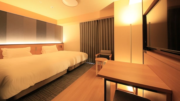 Une chambre d’hôtel avec un grand lit, un bureau, une chaise, une télévision et un rideau.