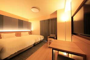 Een hotelkamer met een groot bed, een bureau, een stoel, een televisie en een gordijn.