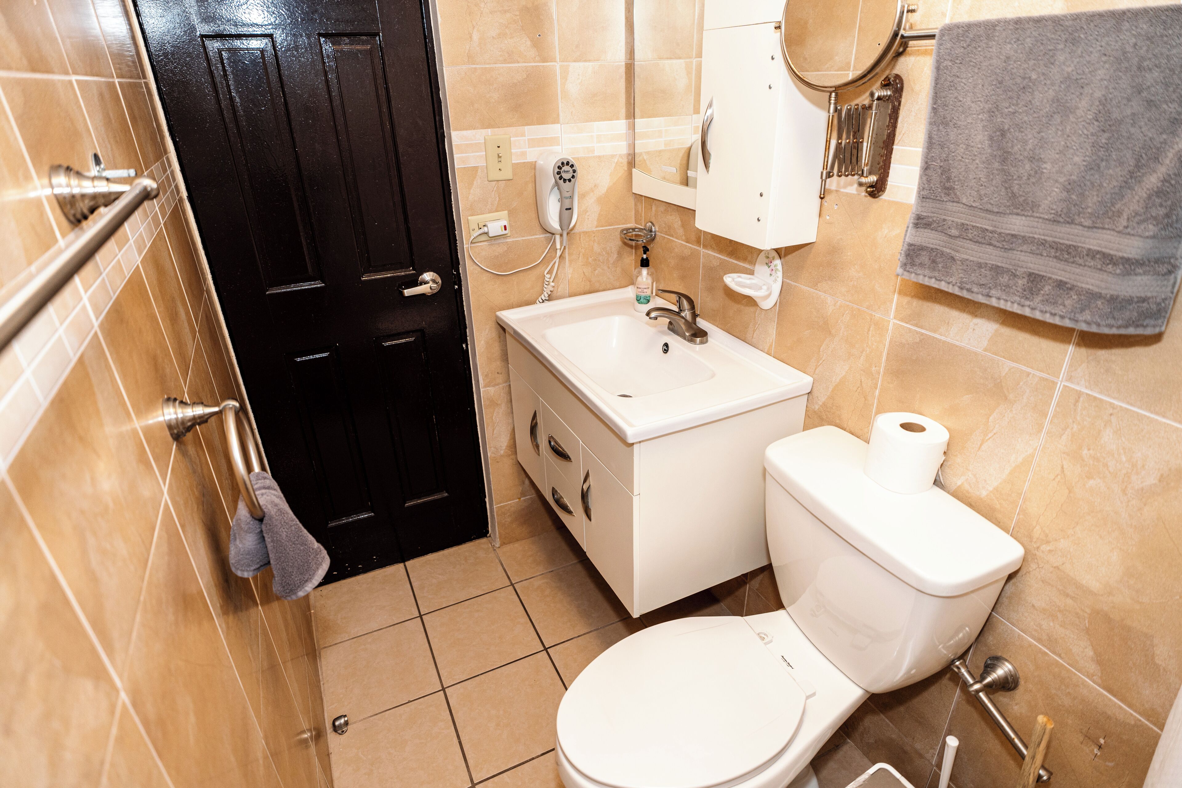 Une salle de bain avec des toilettes, un lavabo et une porte noire.