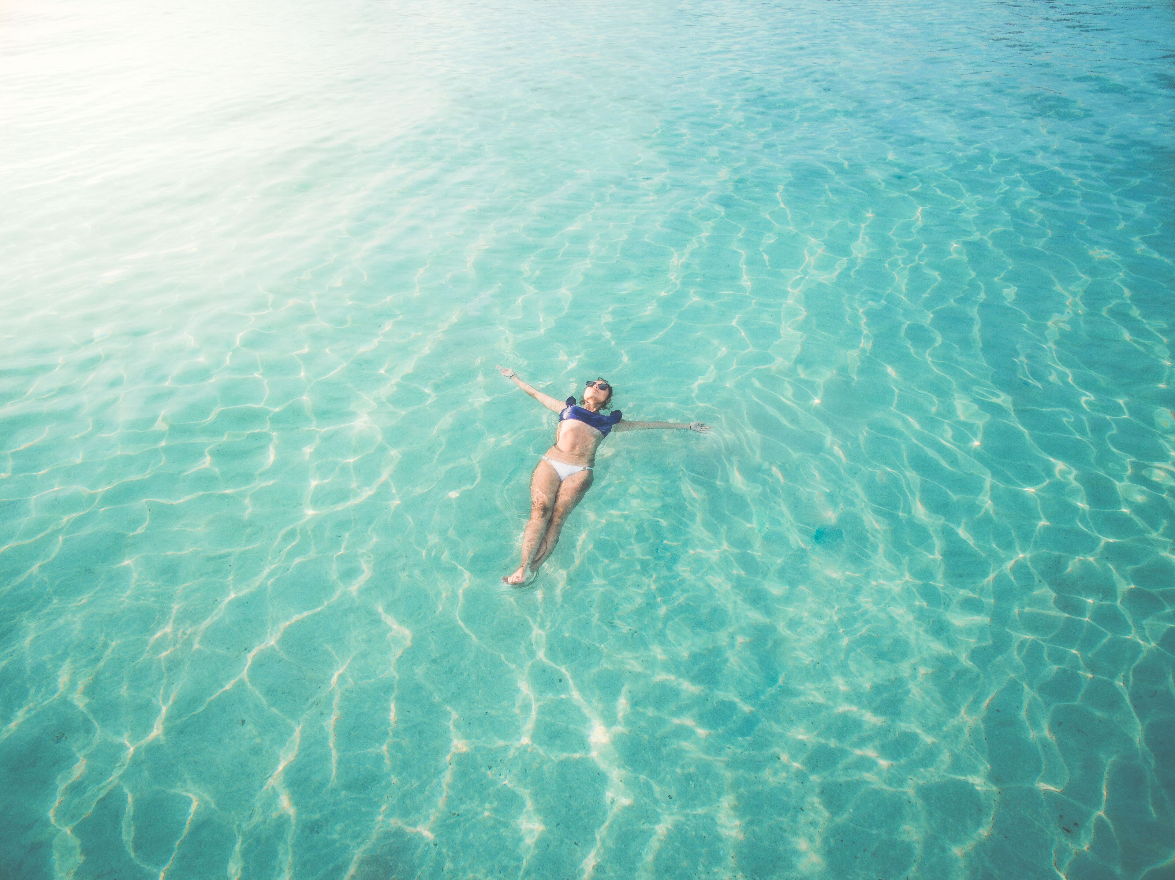 A person floating in clear, shallow water.