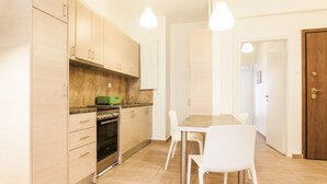 A modern kitchen with wooden cabinets, a dining table with chairs, and pendant lights. - Superb under the Acropolis, walking distance to all attractions,  (Athina)