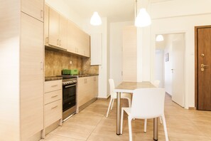 Une cuisine moderne avec des meubles en bois, une table à manger avec des chaises et des luminaires suspendus.