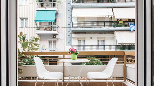 A balcony with two white chairs, a small round table, and a potted plant. - Superb under the Acropolis, walking distance to all attractions,  (Athina)