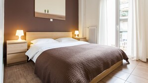 A bedroom with a large bed, two bedside tables with lamps, a wooden headboard, a large window with curtains, and a wall-mounted artwork. - Superb under the Acropolis, walking distance to all attractions,  (Athina)