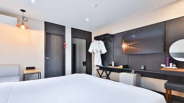 Habitación de hotel moderna con una cama grande, un televisor, un espejo y un escritorio pequeño con artículos de aseo.
