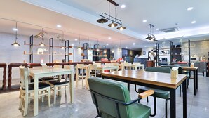 Un restaurante espacioso con varias mesas y sillas, iluminación colgante y un diseño interior moderno.
