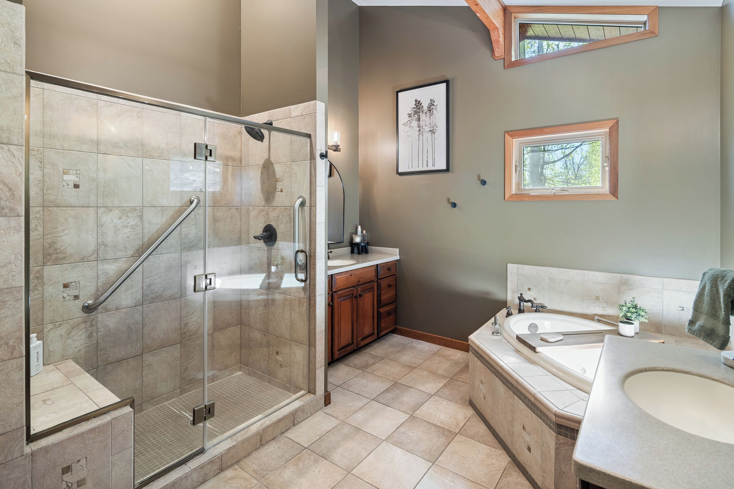 A bathroom with a glass shower, a bathtub, a sink, and a vanity.