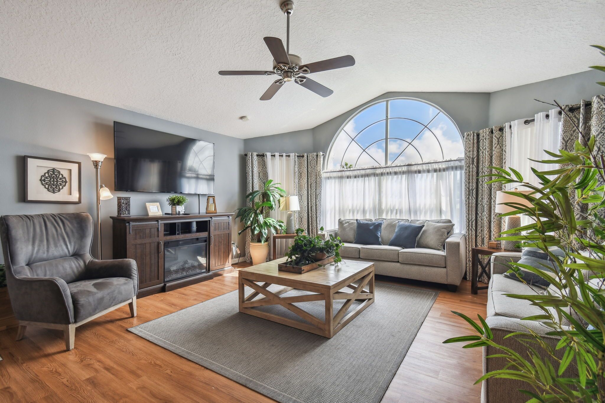 Un salon comprenant un canapé, un fauteuil, une table basse et un ventilateur de plafond.