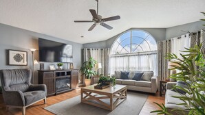 Ein Wohnzimmer mit Sofa, Sesseln, Couchtisch und Deckenventilator.
