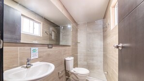 Et badeværelse med vask, toilet og bruser.