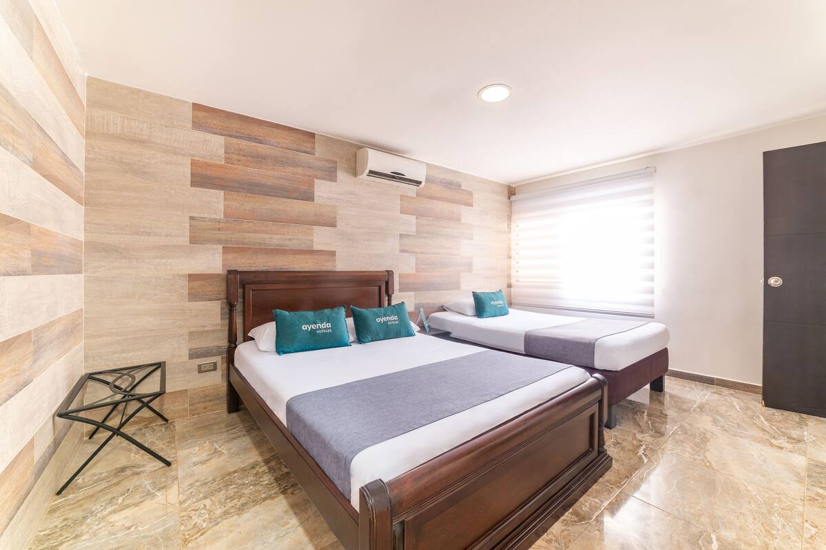 A hotel room with a wooden bed, a smaller bed, and a seating area.