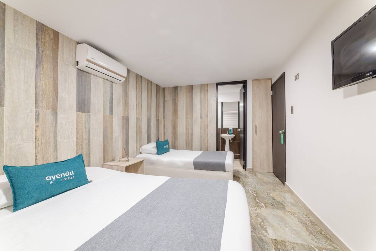 A hotel room with two beds, a bathroom, and a TV.