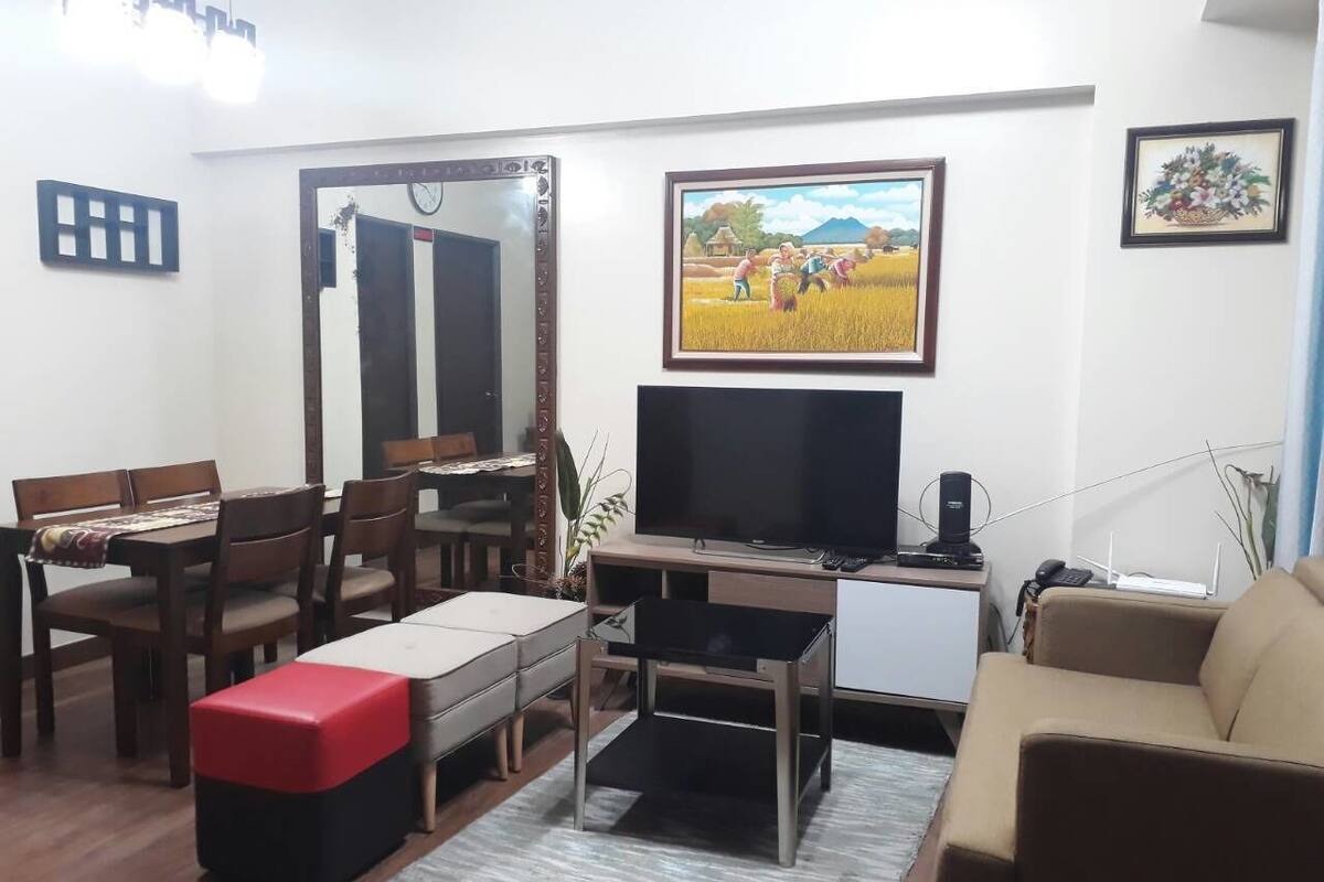 A living room with a TV, dining table, chairs, a sofa, and a coffee table.