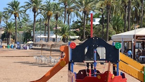 Un parque infantil en la playa con un tobogán y una estructura para escalar.