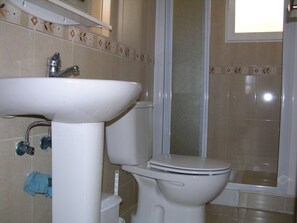 A bathroom with a white sink, toilet, and shower.