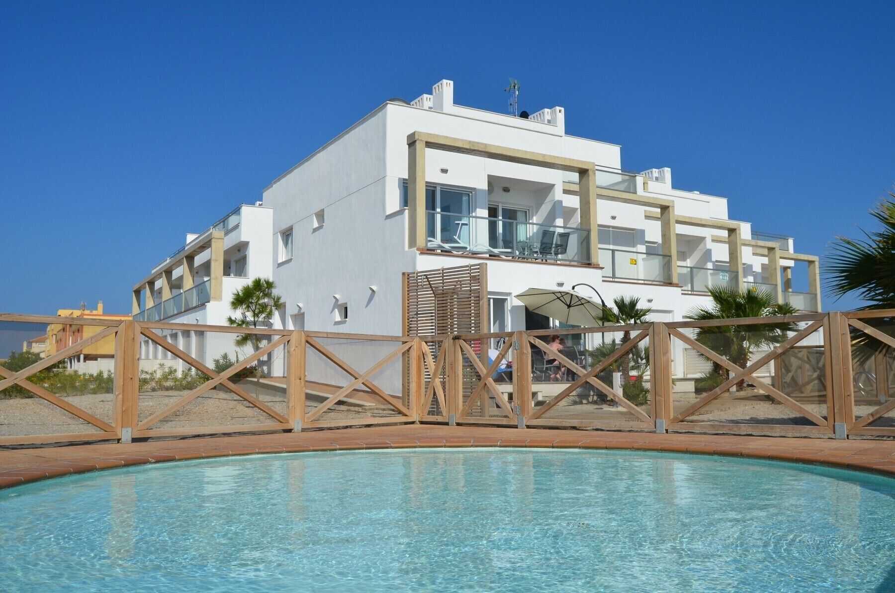 Un bâtiment moderne à deux étages, avec une piscine en premier plan.