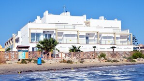 Een wit gebouw met meerdere balkons, nabij een strand.