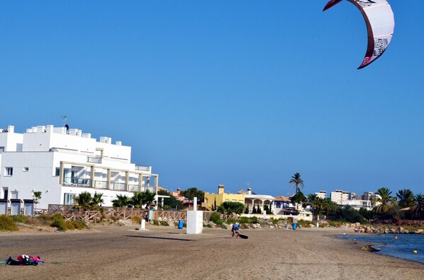 A beach with buildings, a person with a kite, and a clear sky. - 1st floor sea view apartment, free wifi, communal pool (La Manga del Mar Menor)