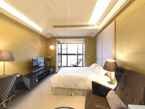 Une chambre d’hôtel moderne équipée d’un lit, d’une télévision, d’un canapé et d’une grande fenêtre.
