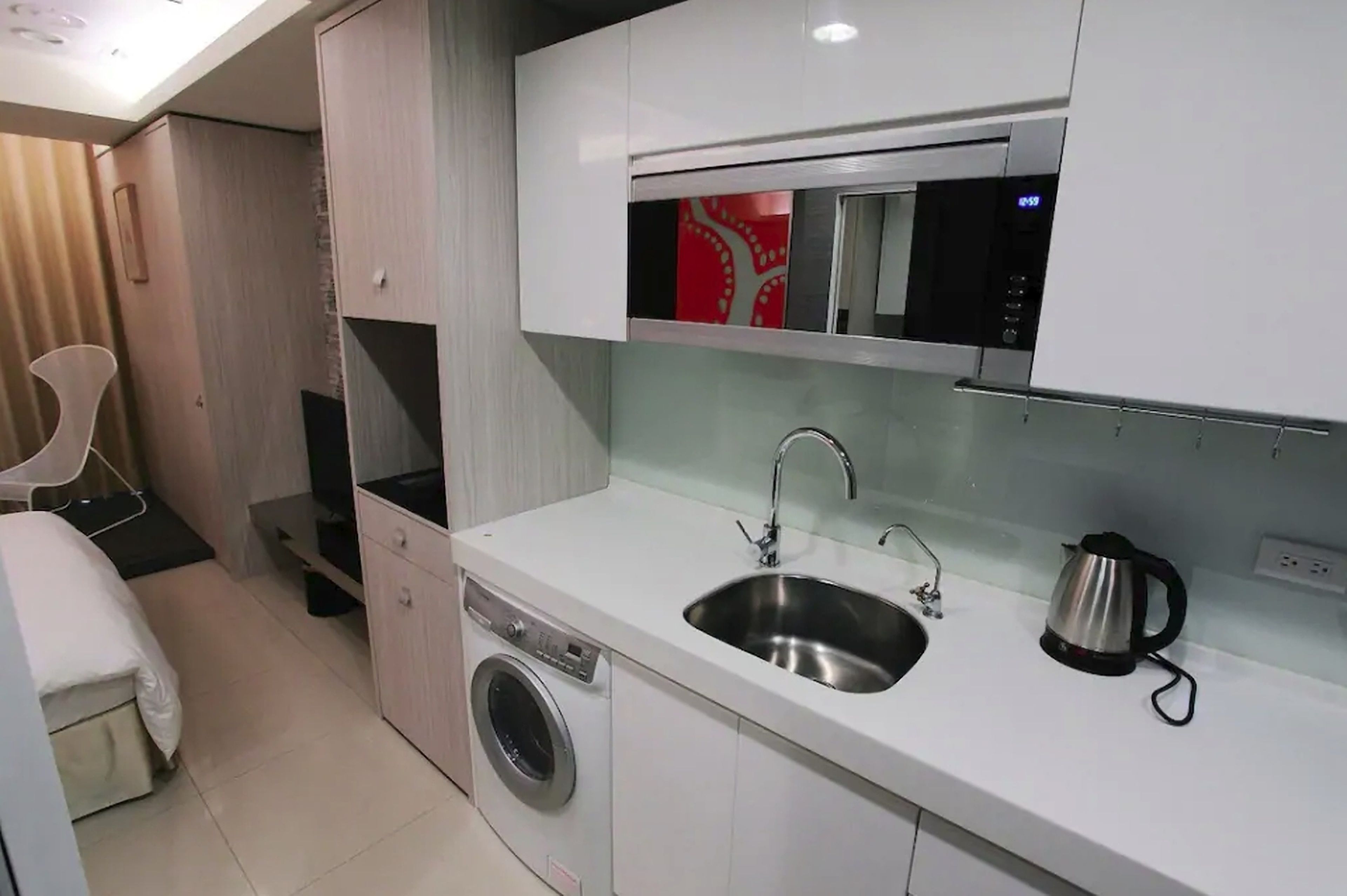A compact kitchenette with a built-in microwave, stainless steel sink, and a kettle.