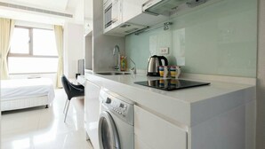 Quarto de hotel compacto com cozinha compacta, máquina de lavar, uma cama e vista para o exterior.