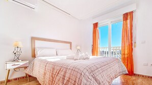 A hotel room with a bed, a nightstand, a lamp, and a window with curtains. - 6th floor apartment ideal for families, free wifi, balcony, sea views (La Manga del Mar Menor)