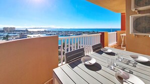 A balcony with a table set for dining, overlooking a marina and cityscape. - 6th floor apartment ideal for families, free wifi, balcony, sea views (La Manga del Mar Menor)
