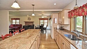 A spacious kitchen with granite countertops, a central island, and a large window. - Little Sandy Pond - Plymouth Estate • Family & Exec Stays • Sleeps 16 (Plymouth)
