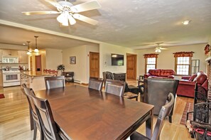 A spacious living area with a dining table, chairs, a fireplace, leather sofas, and a TV.