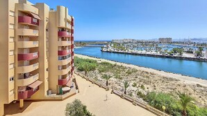 A high-rise building with multiple balconies overlooking a marina and beach. - Family 5th floor apartment, sea views, balcony, communal pool, padel (La Manga del Mar Menor)