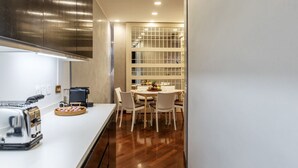 Eine moderne Küche mit einem Edelstahl-Dunstabzug, einer Kaffeemaschine und einem Toaster. Ein Essbereich mit einem Tisch für vier Personen und einer Obstschale.